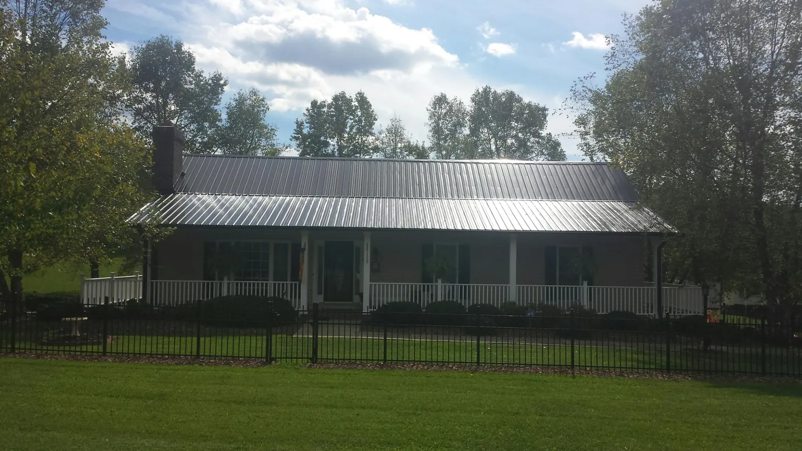 Gray metal roof on a brick ranch with a full width front porch — Gutter Guard Installation work by our crew in Derby